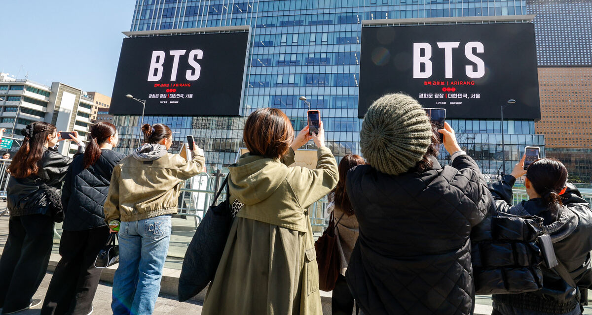 Menjelang konser comeback BTS, warga dan turis asing merekam iklan konser yang ditayangkan di dekat sebuah gedung di dekat Alun-Alun Gwanghwamun di Jongno-gu, Seoul. 