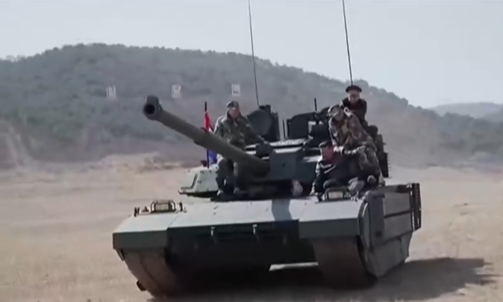 Aksi santai Kim Jong Un duduk di tank yang sedang melaju didampingi sejumlah pejabat militer. 