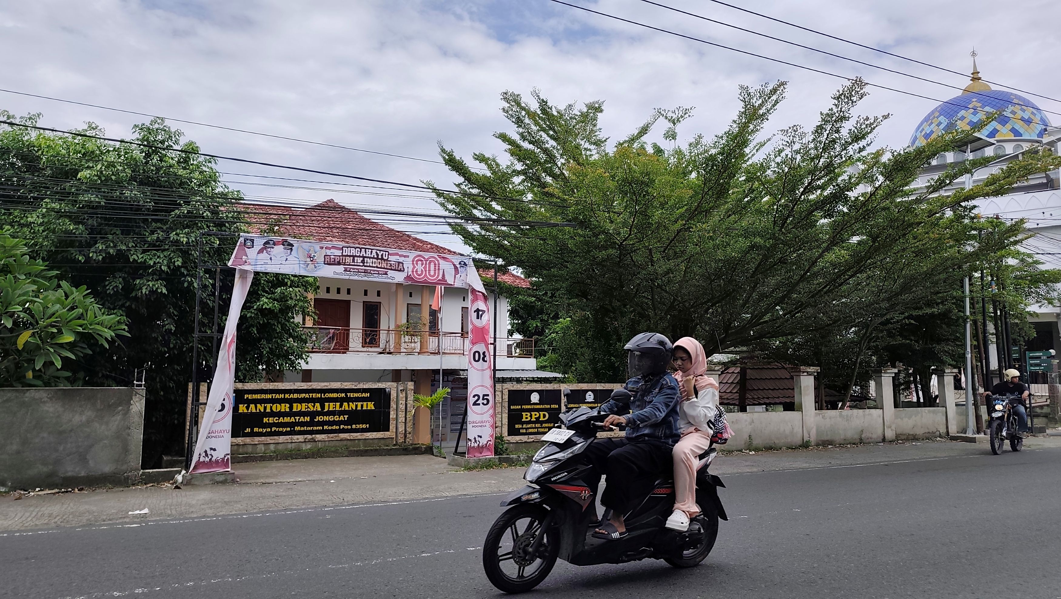 DANA DESA TERTAHAN: Sejumlah pengendara motor melintas di depan kantor Desa Jelantik, Kecamatan Jonggat, Lombok Tengah, Jumat (27/3).