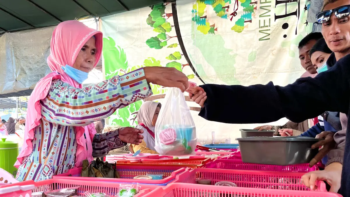 LAYANI PEMBELI: Salah satu pelaku UMKM kuliner di Kota Mataram (kiri) tengah menyerahkan belanjaan konsumen yang dibungkus menggunakan kantong plastik, belum lama ini. (Ferial/Lombok Post)