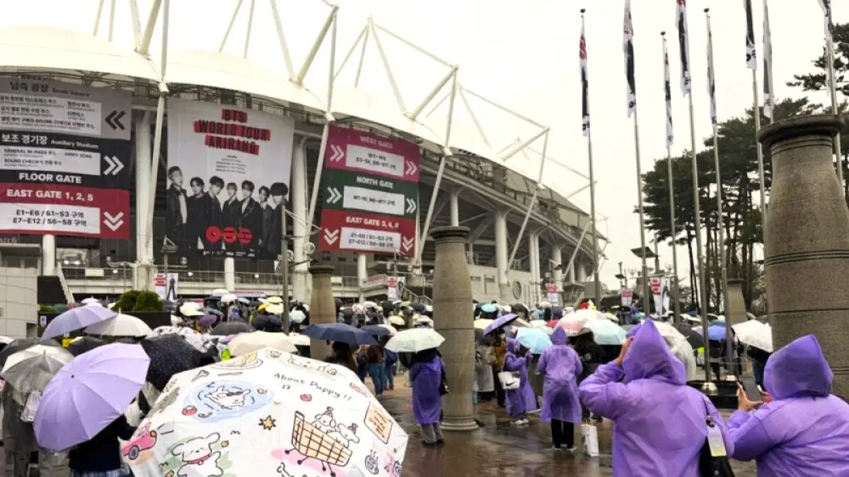 Para ARMY, sebutan penggemar BTS, menggunakan jas hujan warna ungu saat memasuki area konser tur dunai BTS bertajuk ARIRANG di Goyang Stadium, Kamis (9/4). (Allkpop)