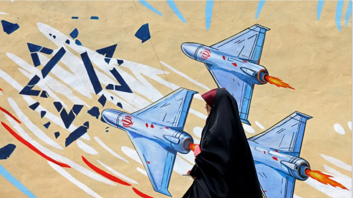Seorang perempuan berjalan melewati mural anti-Amerika Serikat dan anti-Israel di Teheran, Iran pada Rabu, (8/4). (TTA KENARE / AFP)