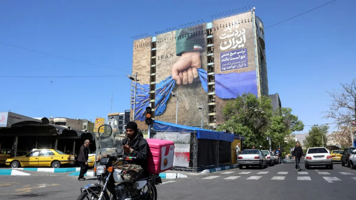 ANCAM RESESI GLOBAL: Seorang pria melewati papan reklame besar yang merujuk pada Selat Hormuz di Lapangan Vanak, Teheran, Rabu (15/4) April 2026. Pada Selasa (14/4), Presiden AS Donald Trump mengatakan bahwa pembicaraan perdamaian AS-Iran dapat dilanjutkan minggu ini. Sementara Israel- Lebanon sepakat untuk memulai negosiasi langsung, menandakan kemajuan di dua front utama dalam upaya meredakan konflik Timur Tengah. (AFP)