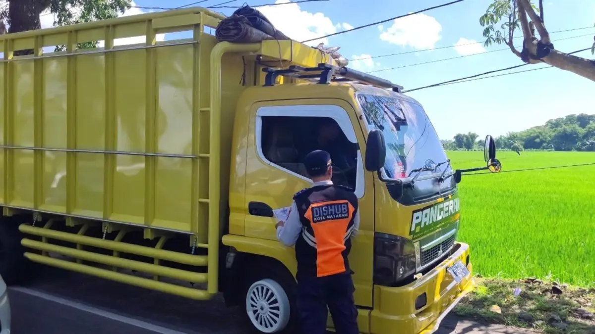 Petugas mengecek surat-surat laik jalan kendaraan truk. 