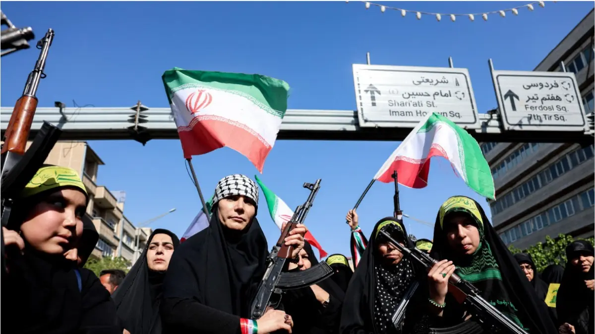 SIAP TEMPUR: Para perempuan Iran mengacungkan senapan saat mengikuti unjuk rasa untuk memberi penghormatan kepada perempuan yang tewas selama perang Timur Tengah di Teheran pada Jumat (17/4). (AFP)