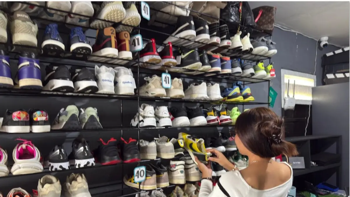 TELITI SEBELUM MEMBELI: Zaeva terlihat memilih dengan teliti sebelum membeli sepatu thrifting, di toko langganannya, belum lama ini. (YUYUN/LOMBOK POST)