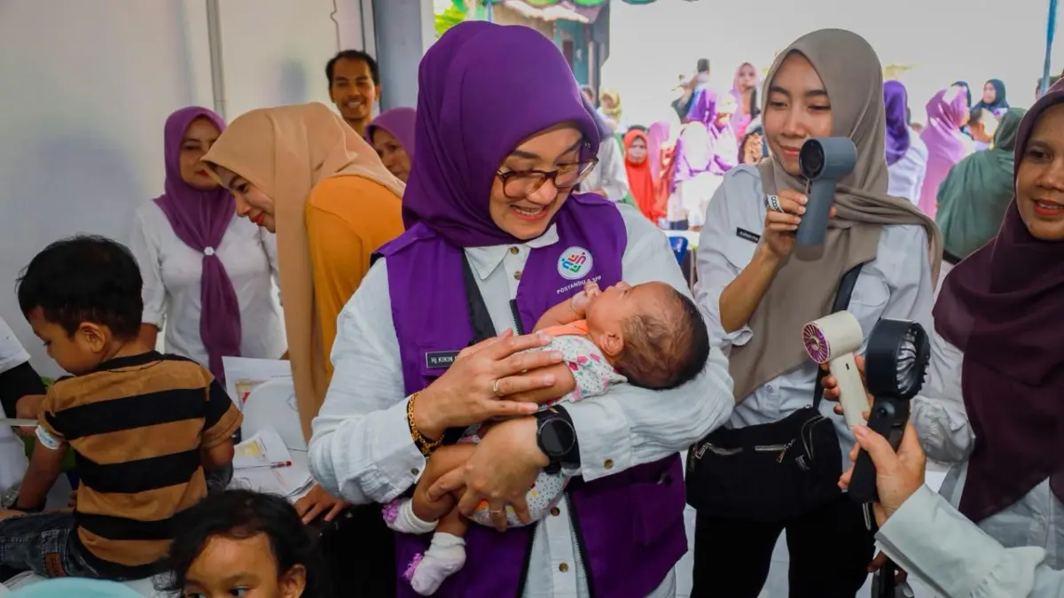 LAYANAN BALITA: Ketua TP Posyandu Kota Mataram Hj. Kinnastri Mohan Roliskana menggendong bayi saat meninjau layanan posyandu. (DOK/KOMINFO)
