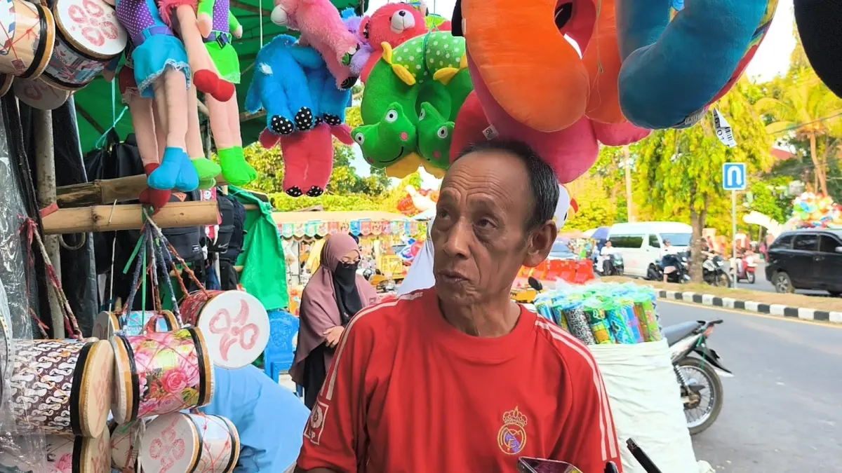 MENGAIS REJEKI: Muhamad pedagang musiman bantal leher di depan Asrama Haji. (CHIA/LOMBOK POST)