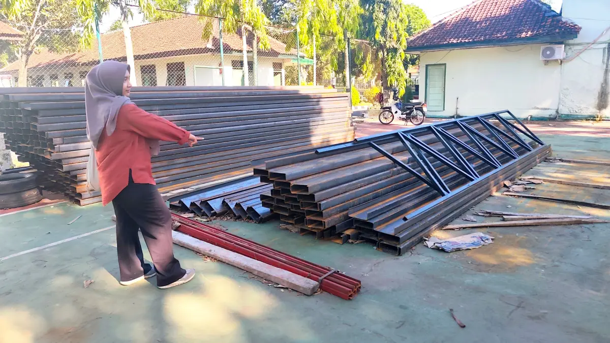  Seorang warga menunjukkan tumpukan besi yang menjadi material bangunan gerai KDKMP di halaman Makodim 1620 Lombok Tengah, Senin (4/5). (Dewi/Lombok Post) 