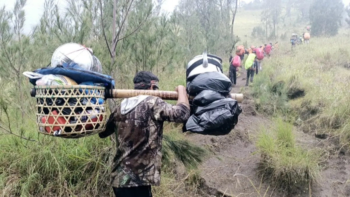 Seorang buruh panggul (porter) memikul barang bawaan pendaki dari arah Sembalun menuju Pelawangan Sembalun di Taman Nasional Gunung Rinjani beberapa waktu lalu.