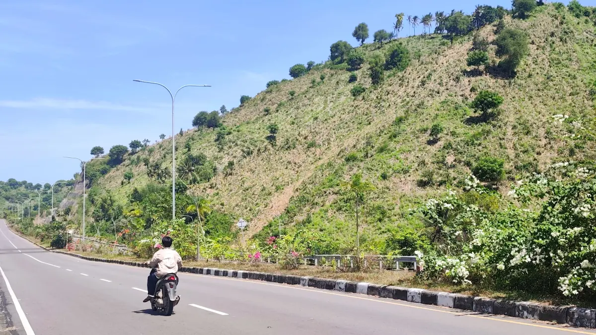 ZONA MERAH: Pengendara bermotor melintasi jalan raya bypass BIL-Mandalika, Senin (11/5). Area perbukitan di sekitar KEK Mandalika masuk radar rawan kebakaran. (Dewi/Lombok Post) 
