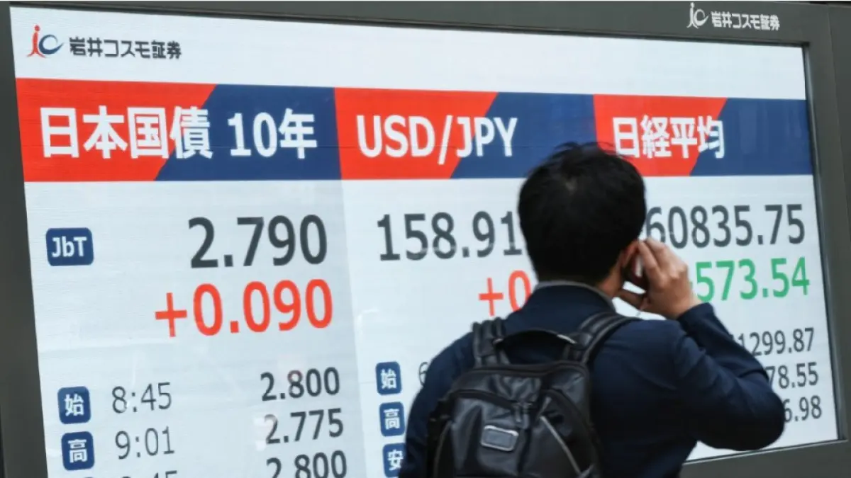 ANJLOK: Seorang pria berjalan melewati papan kutipan elektronik yang menampilkan obligasi pemerintah Jepang, Senin (18/5). Akibat kondisi geopolitik yang belum stabil, bursa saham global anjlok termasuk di Tokyo turun 1 persen. (KAZUHIRO NOGI / AFP)