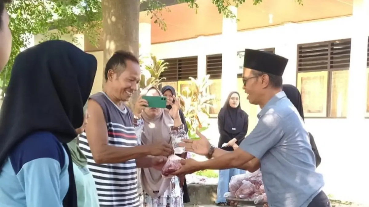 BERQURBAN: Kepala SMPN 3 Tanjung Bulqaini menyerahkan daging qurban kepada masyarakat. SMPN 3 Tanjung menyembelih satu ekor sapi dan tiga ekor kambing.