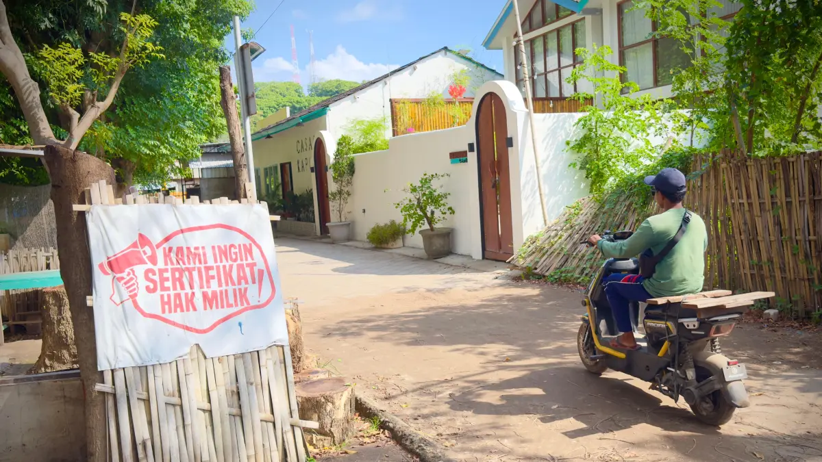 SUARAKAN TUNTUTAN: Seorang warga melintas di depan spanduk yang bertuliskan Kami Ingin Sertifikat Hak Milik yang terpampang di salah satu sudut, di Gili Trawangan, Minggu (24/5). 