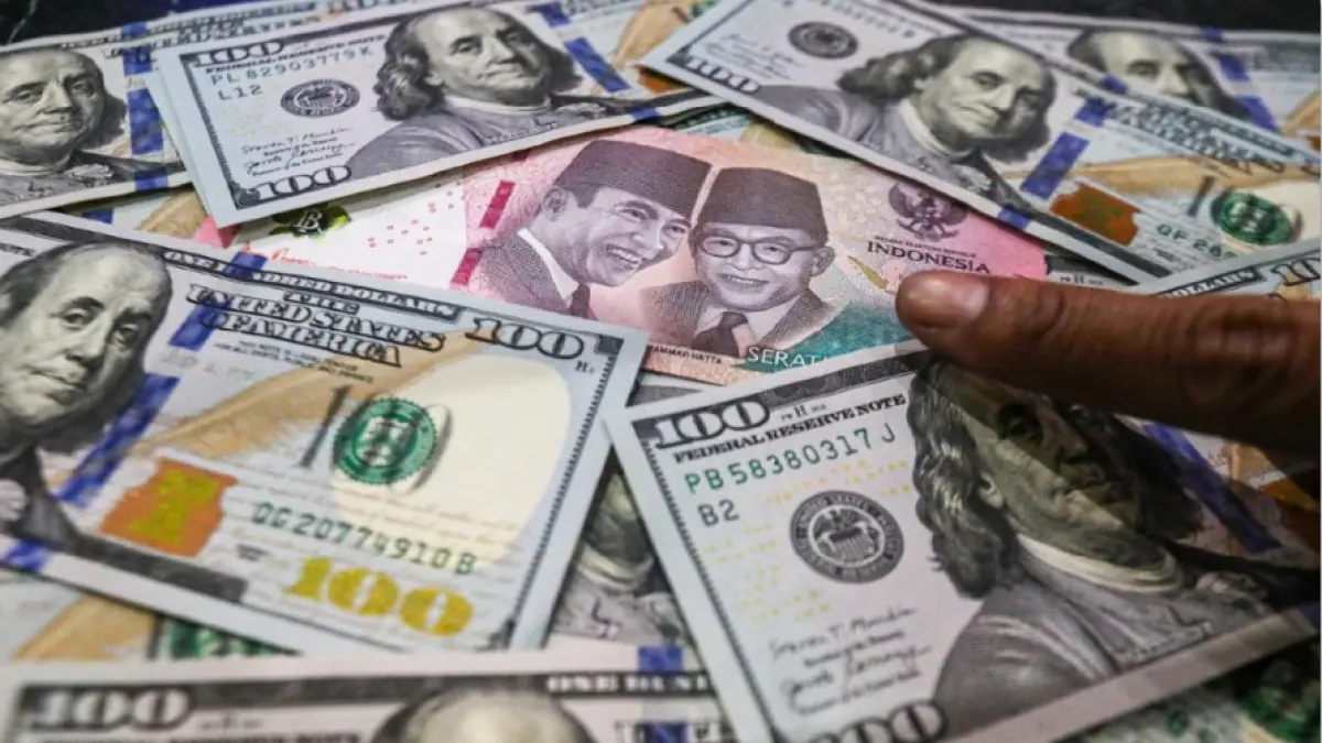KEBIJAKAN BARU: Tampak uang rupiah pecahan seratus ribu di antara uang dolar Amerika Serikat (AS) pecahan seratus di gerai penukaran mata uang asing Dolar Asia, Jakarta, Selasa (12/5). Pemerintah resmi memberlakukan aturan baru mengenai penempatan DHE SDA mulai Senin (1/6). Kebijakan itu diyakini bisa menambah likuiditas valas di perbankan nasional. Selain itu juga bisa menjaga stabilitas nilai tukar rupiah. (SALMAN TOYIBI/JAWA POS)