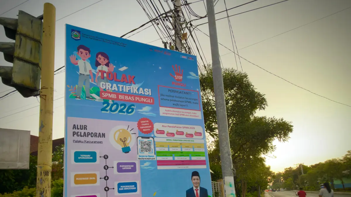 PERINGATAN: Warga melintas di depan baliho yang menampilkan kampanye tolak gratifikasi dan bebas pungli, selama SPMB 2026, di depan kantor Dikpora NTB, Jumat (5/6). 