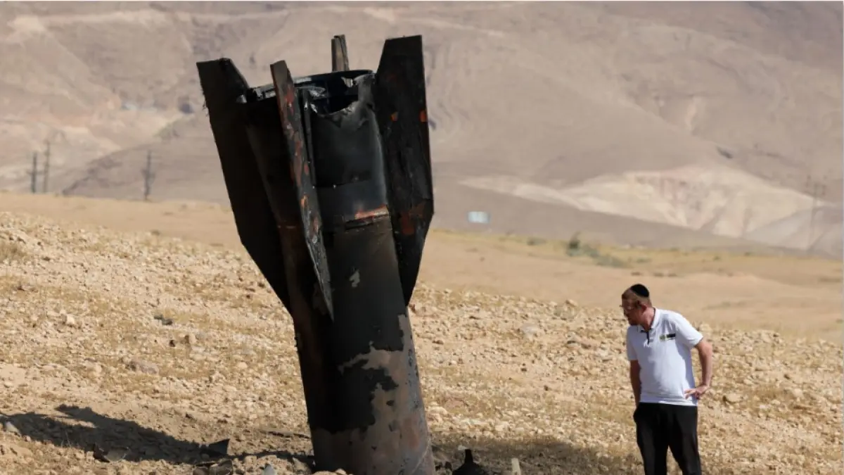 RUDAL IRAN: Seorang pria memeriksa roket sisa serangan Iran ke Israel yang jatuh di pinggiran Kota Jericho, Senin (8/6) lalu. Iran-Israel kembali saling serang di tengah perundingan Iran-AS. (AHMAD GHARABLI / AFP)