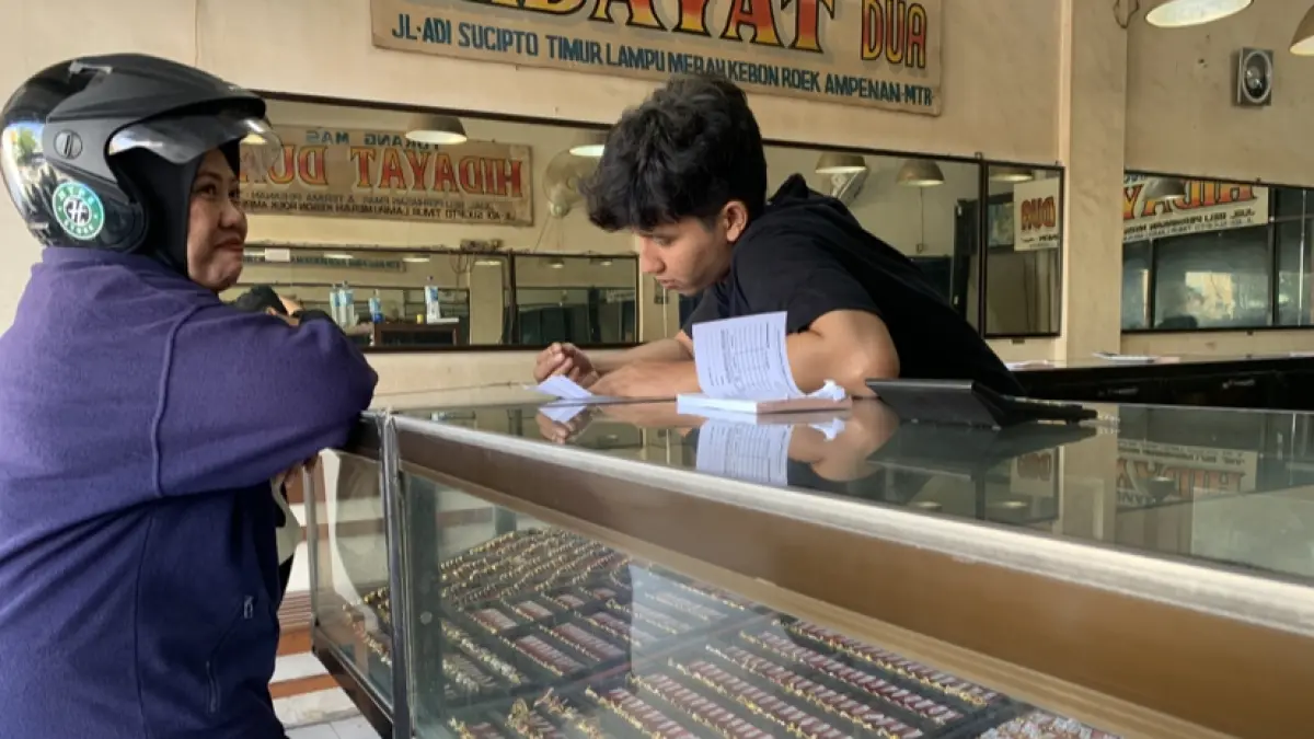 Seorang ibu rumah tangga menjual emasnya di toko emas Pasar Kebon Roek