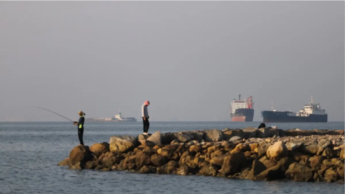 DITUTUP: Warga memancing dari tepi pantai, sementara kapal kargo dan kapal komersial berlabuh di Selat Hormuz di lepas pantai Bandar Abbas, Senin (8/6). Iran kembali menutup total Selat Hormuz. (AMIRHOSSEIN KHORGOOEI / ISNA / AFP)
