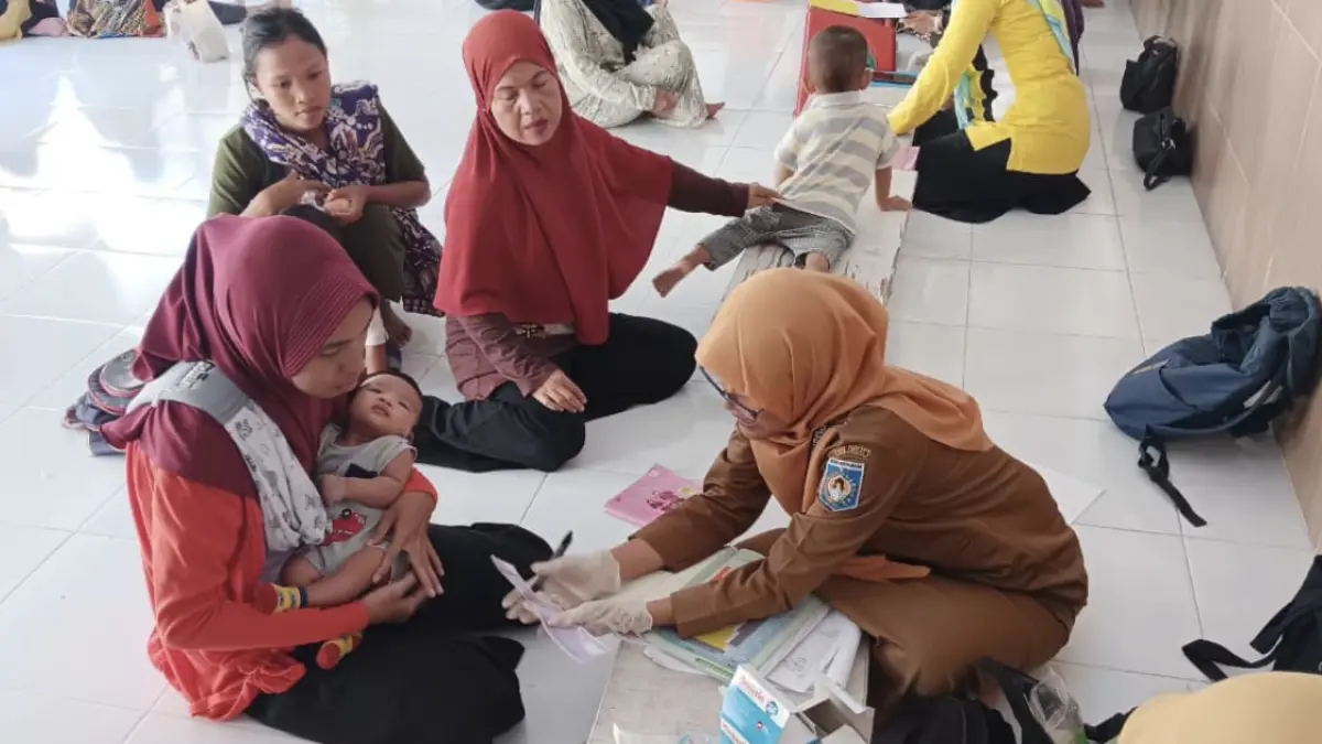 Mimin Minkhatul Maula S.Kep, Ners. saat menggunakan MANDALIKA SIP, media edukasi berbentuk mistar yang membantu orang tua memahami jadwal imunisasi anak di wilayah kerja Puskesmas Ampenan, beberapa waktu lalu. 