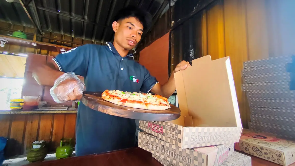 Seorang karyawan Meydifood memasukkan pizza siap santap ke dalam boks pesanan konsumen. Lapak pizza ini berlokasi di sebelah timur Alun-Alun Tastura Kota Praya, Lombok Tengah. (Dewi/Lombok Post) 