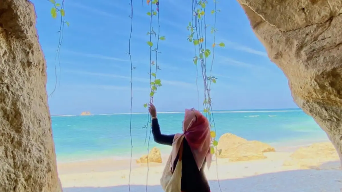 Seorang pengunjung berswafoto dengan latar pemandangan pantai dari dalam goa Pantai Kaliantan, Desa Seriwe, Kecamatan Jerowaru, Lombok Timur, Selasa (9/6). (Dewi/Lombok Post) 