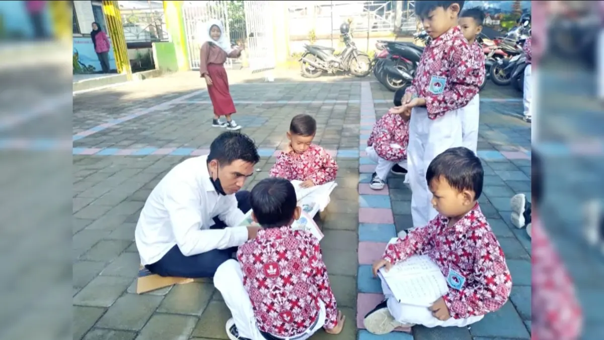 Seorang guru tengah mendampingi anak didiknya belajar di luar ruangan, memastikan mereka memahami pelajaran dengan sebaik-baiknya.  