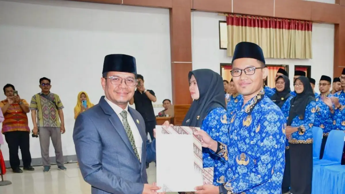 Bupati Dompu Bambang Firdaus (kiri) menyerahkan SK kepada salah seorang PNS, Kamis (18/6).