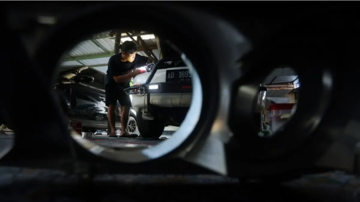 PASANG LAMPU: Karyawan Yoong Motor Lombok memasang lampu LED di bengkelnya di Jalan Pisang 3 Mayure, Cakranegara, Kota Mataram, Jumat (19/6).&nbsp;(IVAN/ LOMBOK POST&nbsp;)