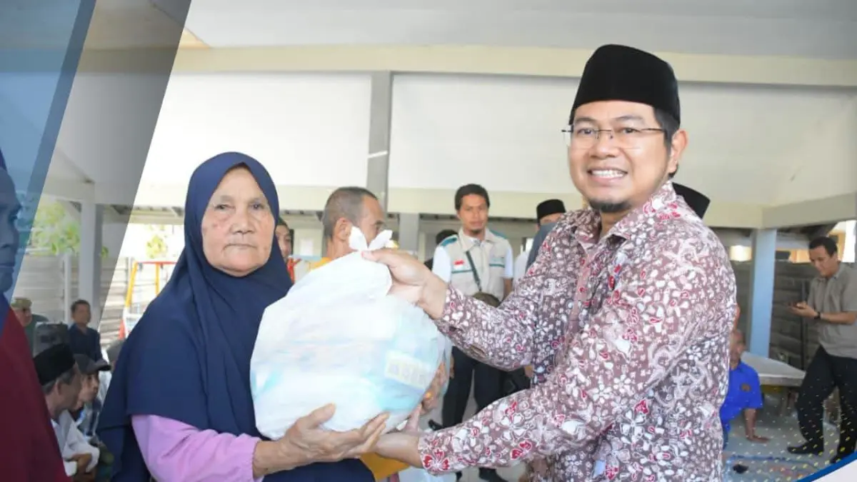 TERIMA BANTUAN: Seorang warga Dusun Teluk Kombal, Desa Pemenang Barat menerima paket sembako, kemarin