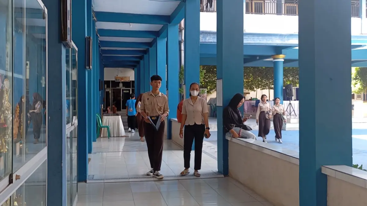 DAMPINGI ANAK: Seorang wali murid mendampingi anaknya memgambil rapor di SMPN 15 Mataram, Jumat (19/6).