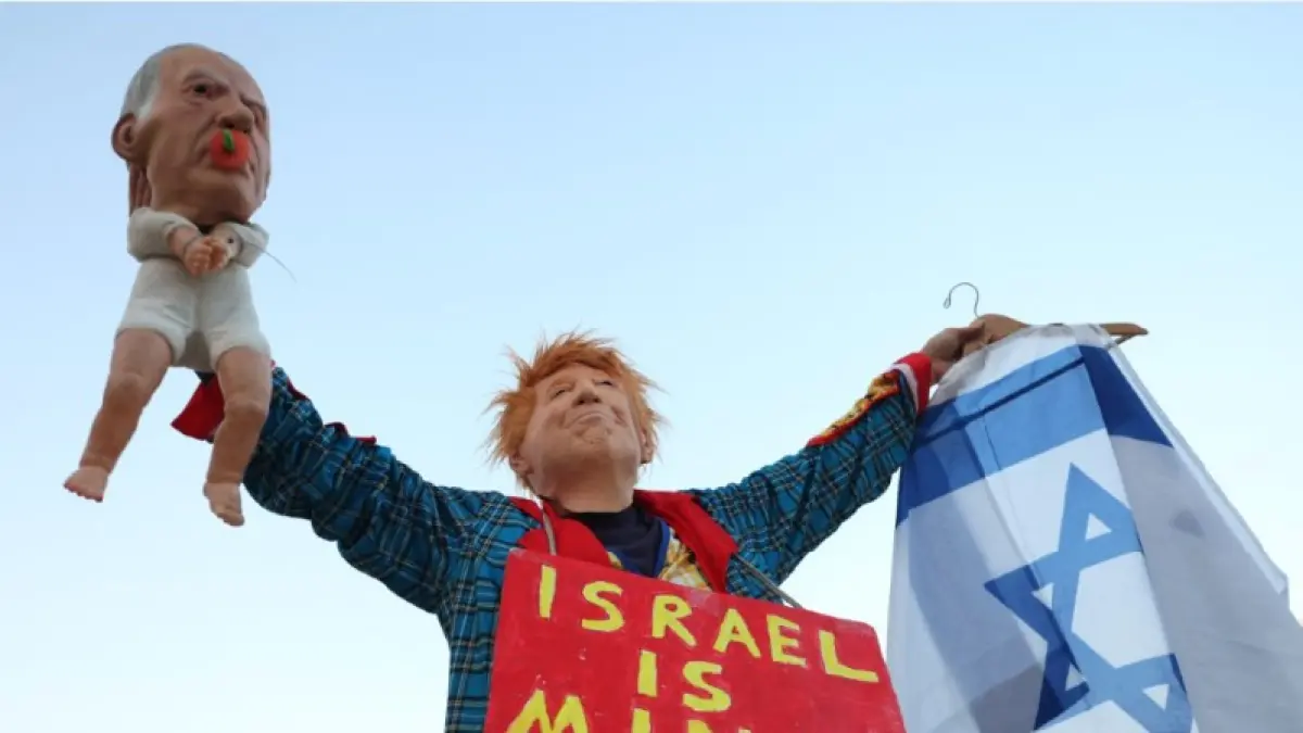 PROTES: Seorang aktivis Israel mengenakan kostum dengan topeng yang menggambarkan Presiden AS Donald Trump memegang boneka bayi yang menggambarkan Perdana Menteri Israel Benjamin Netanyahu saat demonstrasi menentang rezim Netanyahu di Israel, Selasa (16/5). (JACK GUEZ/AFP)
