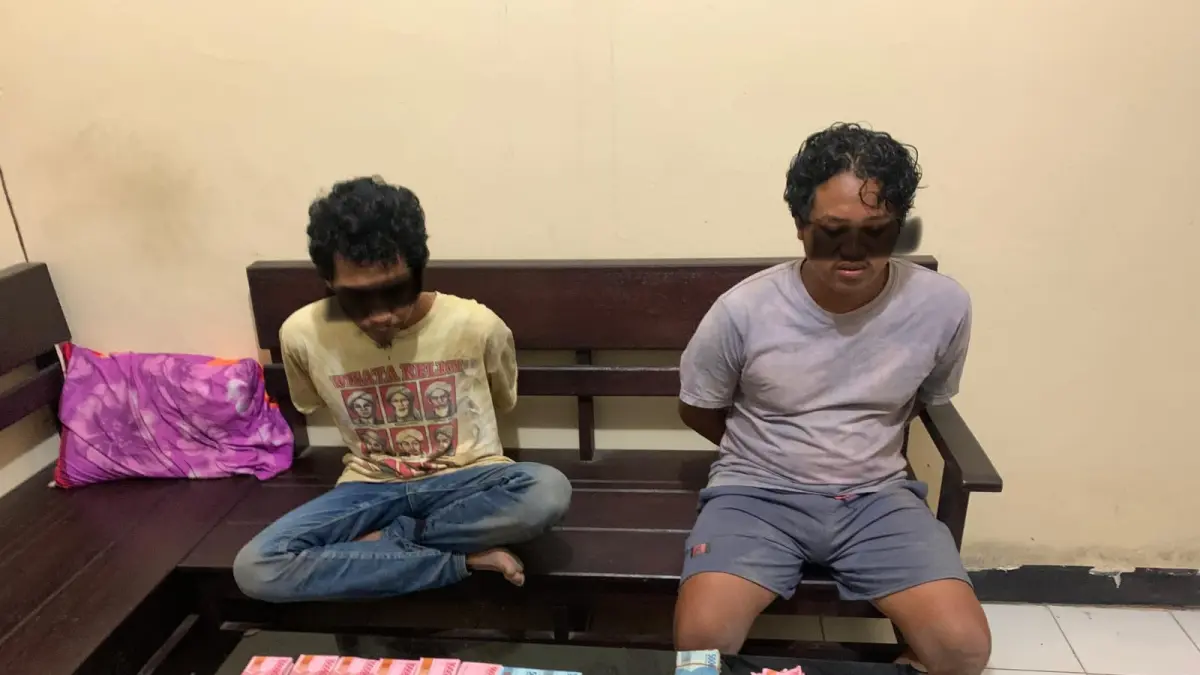 TERDUGA PELAKU: Dua orang terduga pelaku pengedar uang palsu saat diamankan di Polsek Sakra