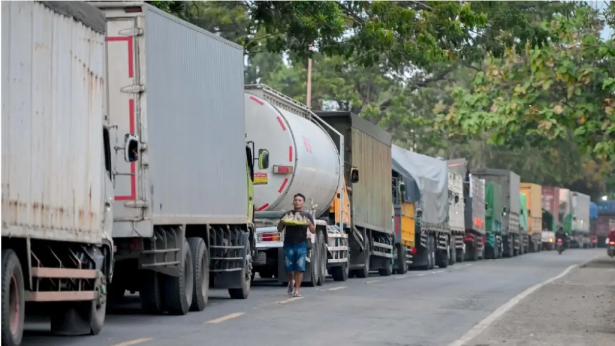 MENGULAR: Antrean kendaraan pengangkut logistik masih memadati jalan raya depan depo Pertamina, Ketapang, Banyuwangi, Rabu (24/6). Panjang antrean kendaraan mencapai 7,7 kilometer. (Jawa Pos)