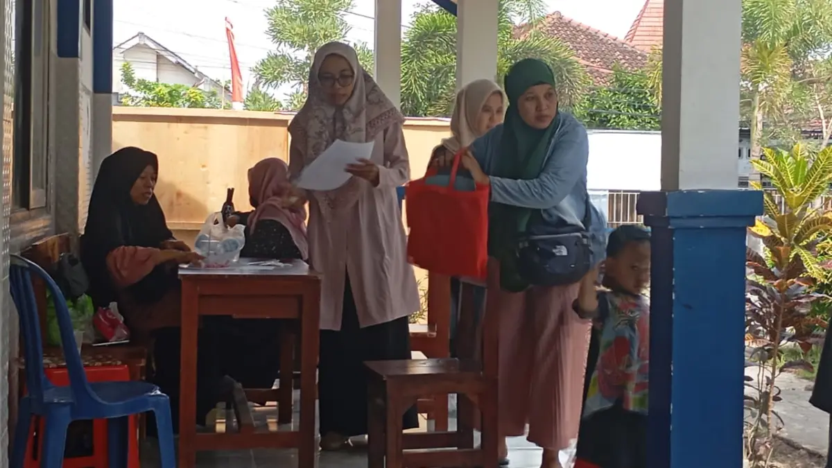 AMBIL SERAGAM: Seorang wali murid mengambil seragam gratis di SMPN 23 Mataram, Kamis (25/6).

