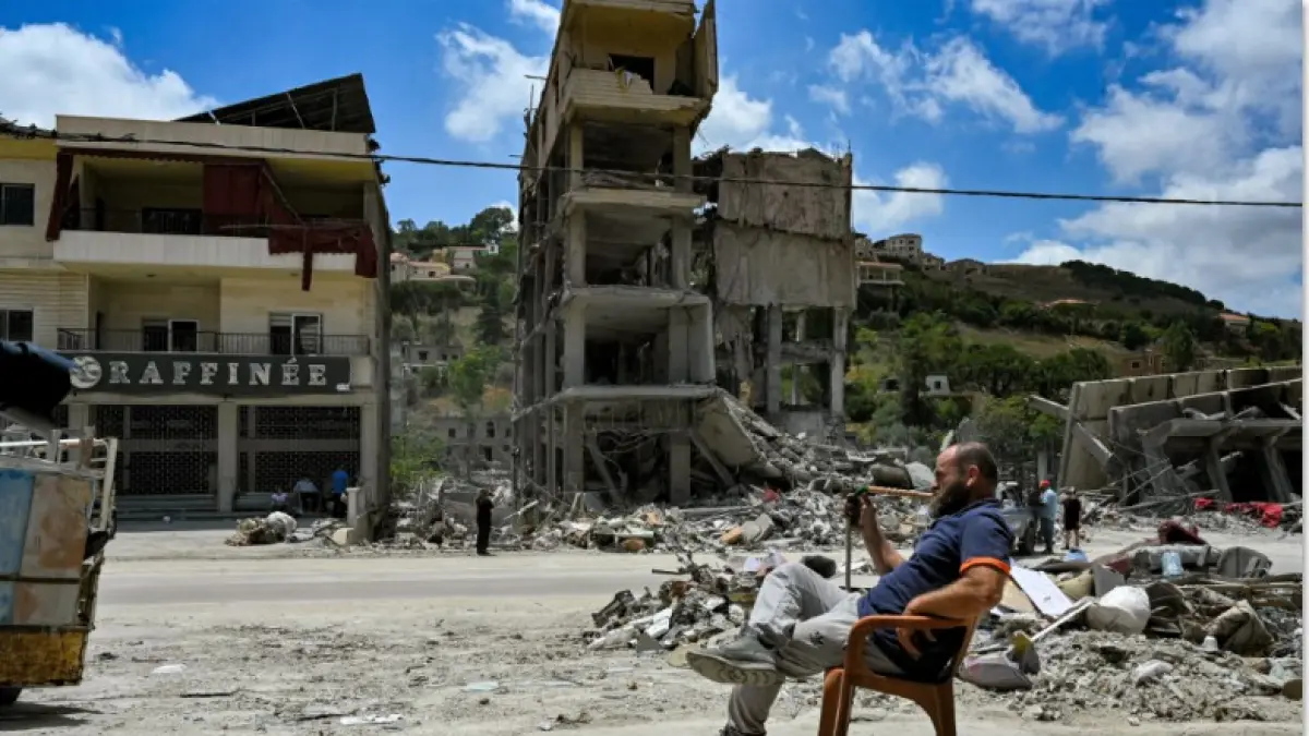 KORBAN PERANG: Seorang pria duduk di dekat puing-puing bangunan akibat serangan Israel di Kota Nabatieh, al-Fawqa, Lebanon pada Selasa (23/6). Netanyahu juga mengumumkan akan menyerang Iran. (FADEL ITANI/AFP)