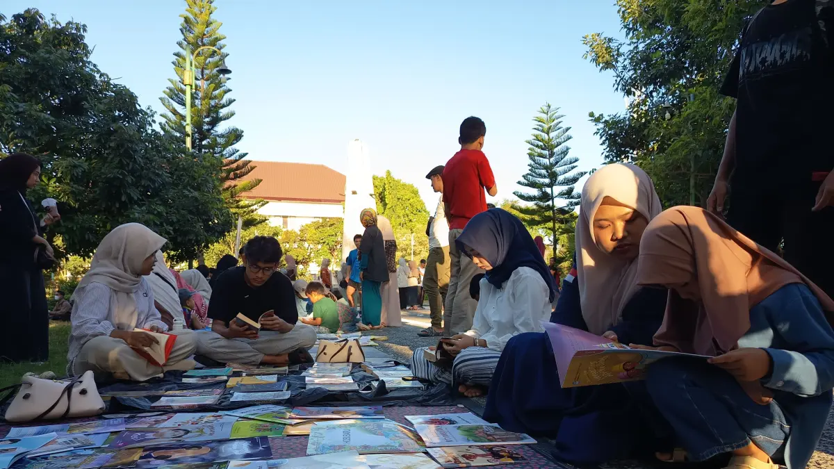 BACA BERSAMA: Salah seorang anak sedang membaca buku di zona baca nyaring yang disiapkan komunitas literasi di Lombok Timur saat acara baca bersama di Taman Tugu Selong. 