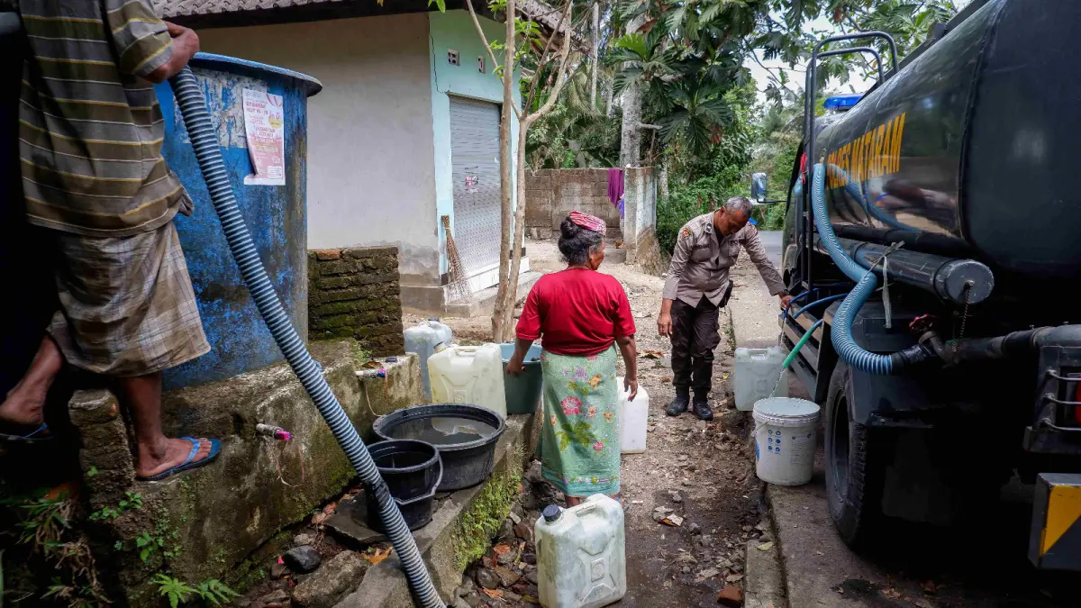 DAMPAK KEKERINGAN: Seorang personel kepolisian membantu membagikan air bersih, kepada warga terdampak kekeringan, beberapa waktu lalu. (IVAN/LOMBOK POST)