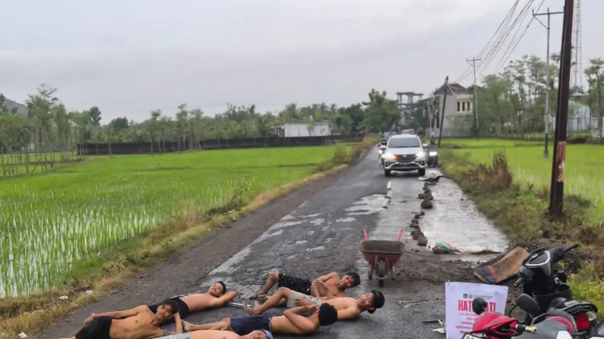 KELUHKAN JALAN: Sejumlah pemuda berbaring di atas jalan raya wisata Selong Belanak karena kondisi jalan yang rusak parah akibat lalu lalang kendaraan truk, pekan lalu.