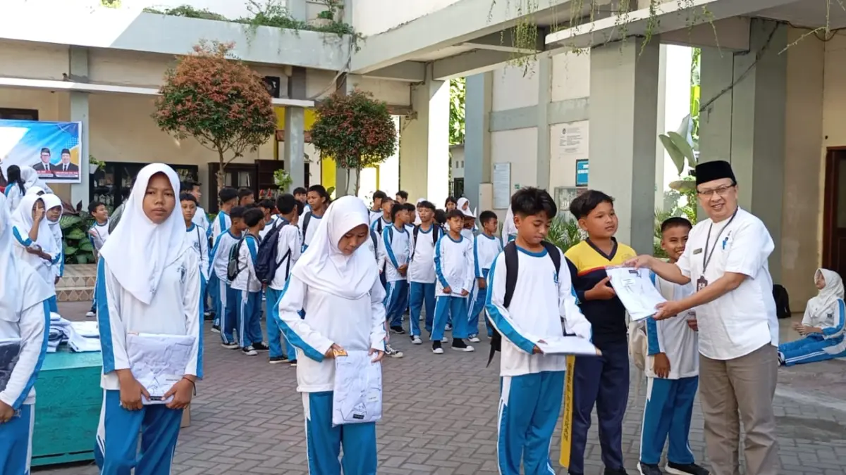 SERAGAM GRATIS: Plt Kepala SMPN 6 Mataram Cahyo Wirawan (pakai peci) memberikan seragam gratis kepada siswa baru jalur afirmasi pada kegiatan pra MPLS di sekolah setempat, Jumat (10/7).