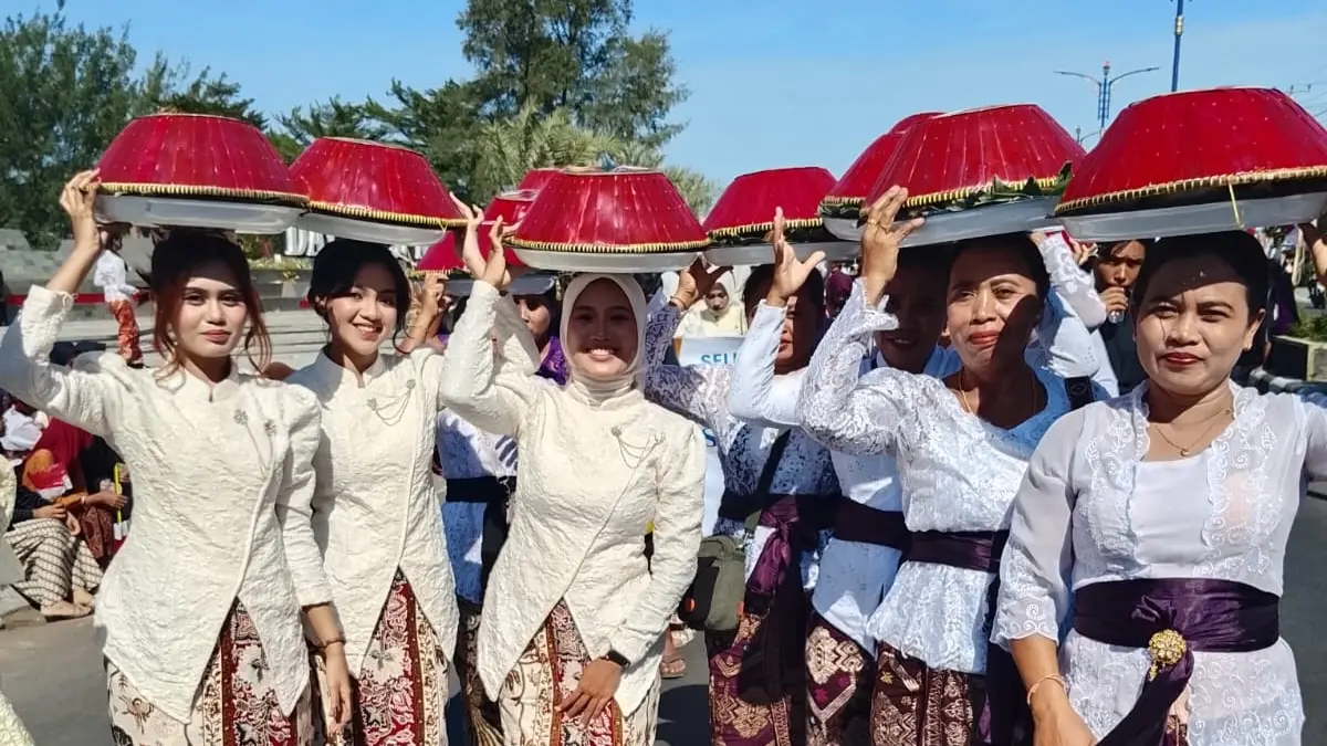 MERAMAIKAN: Peserta parade desa dari Desa Bentek membawa dulang dari makanan khas tradisional setempat.