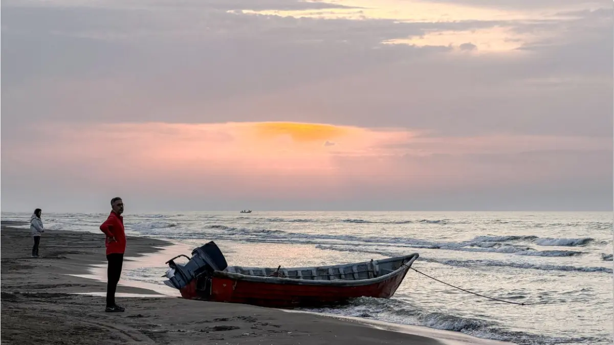 MENEPI: Seorang pria berdiri di dekat perahu di tepi pantai Laut Kaspia di Iran utara beberapa waktu lalu. Seorang pelaut Iran tewas akibat serangan Ukraina, Sabtu (25/7). (AFP)