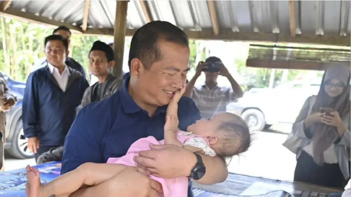 BERI PERHATIAN: Gubernur NTB Lalu Muhamad Iqbal menggendong bayi penderita hidrosefalus di Dusun Kreak, Desa Pandan Indah, Kabupaten Lombok Tengah, Senin (27/7). (DISKOMINFOTIK NTB/LOMBOK POST)