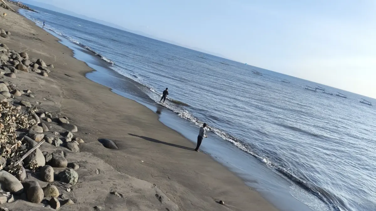 Dua pemancing di pantai Boom Ampenan tengah menunggu umpan di makan ikan.