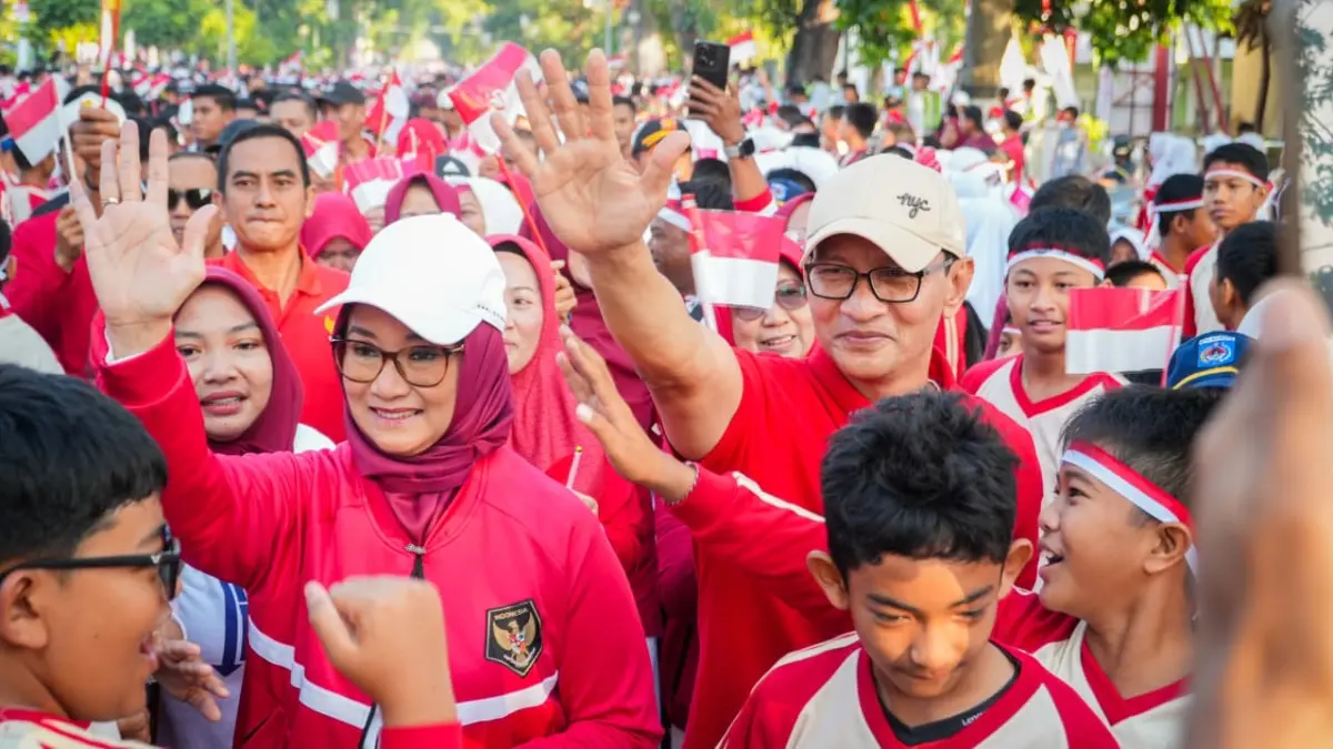 Wali Kota Mataram Mohan Roliskana dan Ketua TP PKK Kota Mataram Kinnastri Mohan Roliskana di antara warga dan anak-anak yang menyemarakkan parade bendera merah putih.