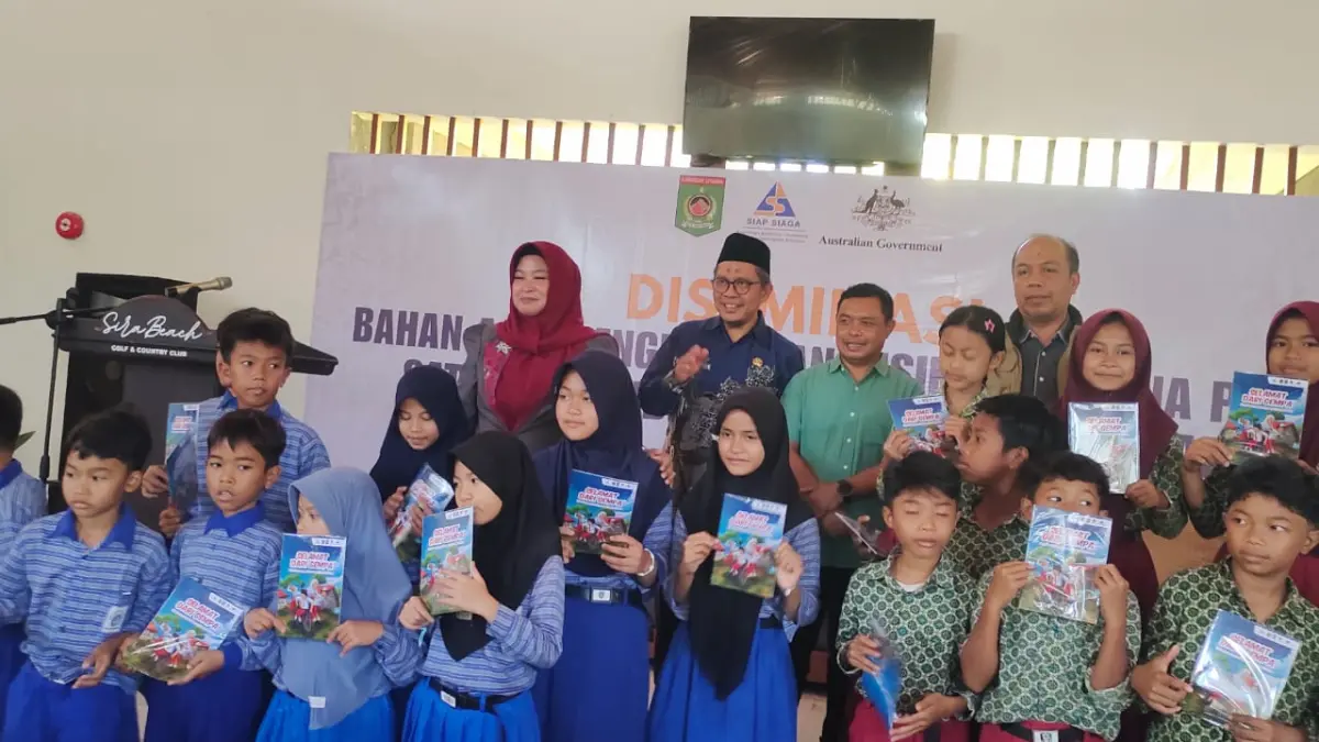 PENGENALAN SEJAK DINI: Para siswa menunjukkan buku bahan ajar risiko bencana yang diberikan pada acara diseminasi.