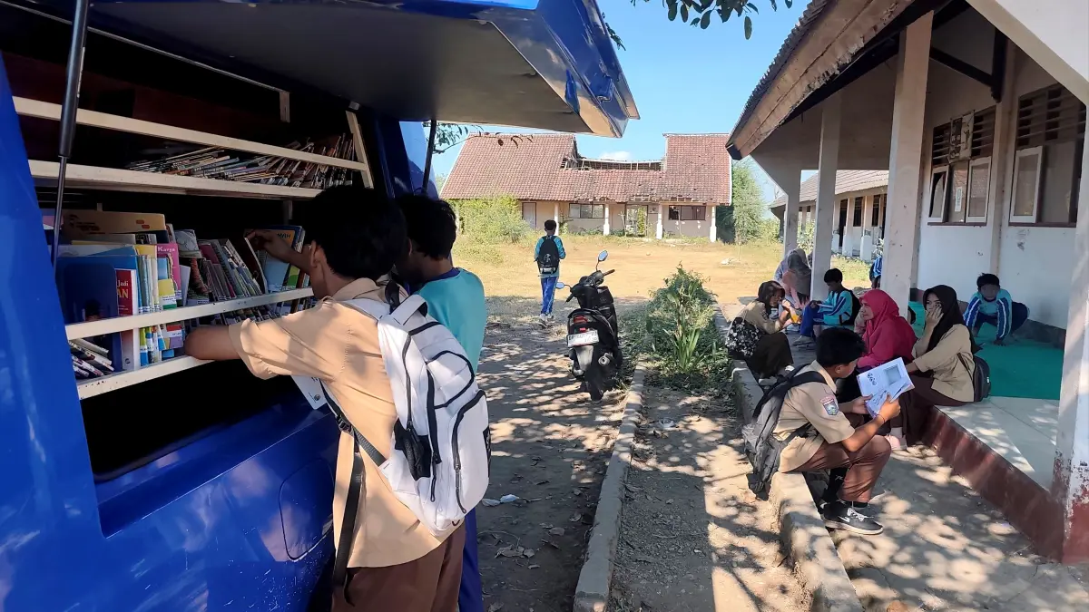 Sejumlah murid memilih beberapa buku yang hendak dibaca saat mobil perpustakaan keliling hadir di halaman SMPN 5 Praya Timur, Desa Beleke Lebe Sane, Praya Timur, Lombok Tengah, Kamis (13/8). Ini disebabkan sekolah tersebut tidak memiliki ruang perpustakaan yang layak.