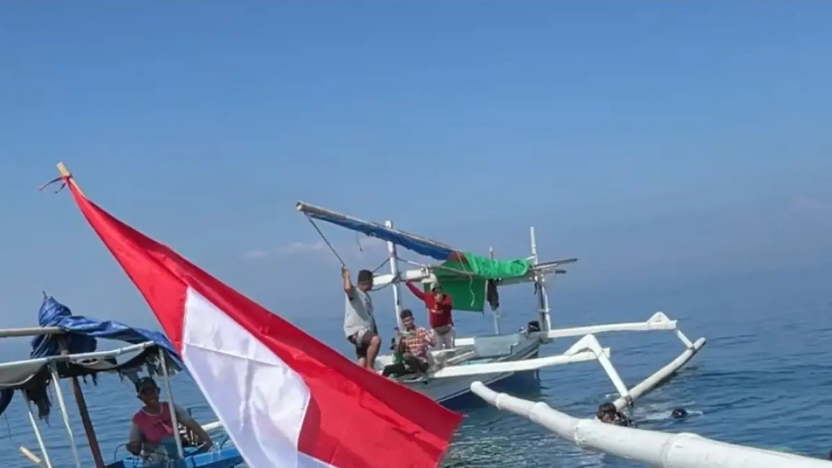 Seorang penyelam scuba KKP memegang bendera merah putih saat bersiap menyelam untuk mengibarkannya di dasar laut Ampenan.