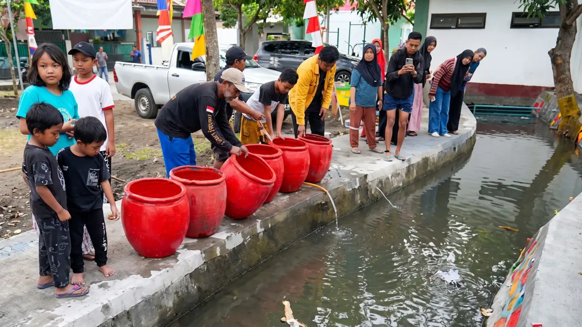 Warga saat melepas benih ikan ke saluran air yang sudah dibersihkan.