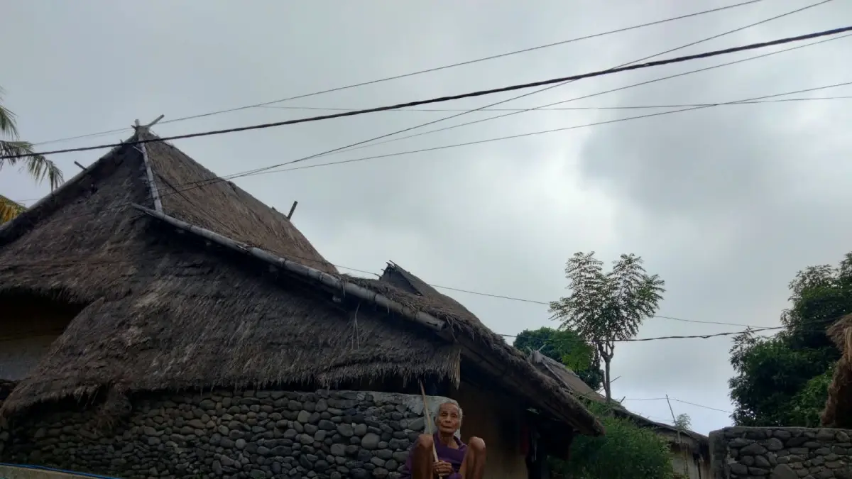 BALE ADAT: Salah seorang warga yang masih menempati rumah adat sedang duduk di depan rumahnya di Limbungan Barat, Desa Perigi Kecamatan Suela, Lombok Timur. 